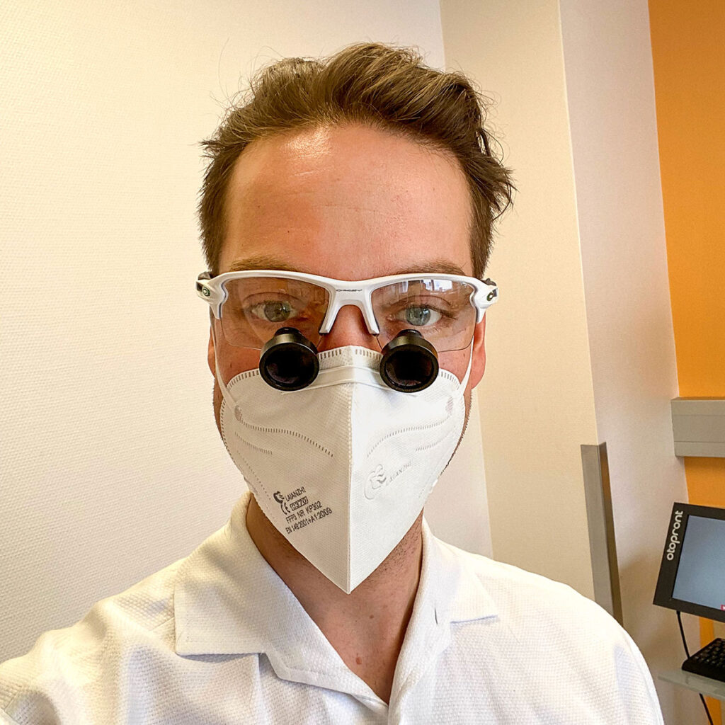 HNO-Arzt OA Dr. Philipp Wimmer mit einer Lupenbrille in seiner HNO-Ordination in 1100 Wien, direkt neben der Therme Wien